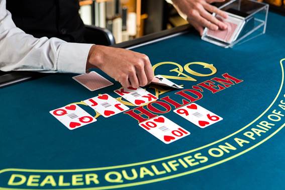 An Evolution dealer lays out the community cards in a game of Casino Hold’em online